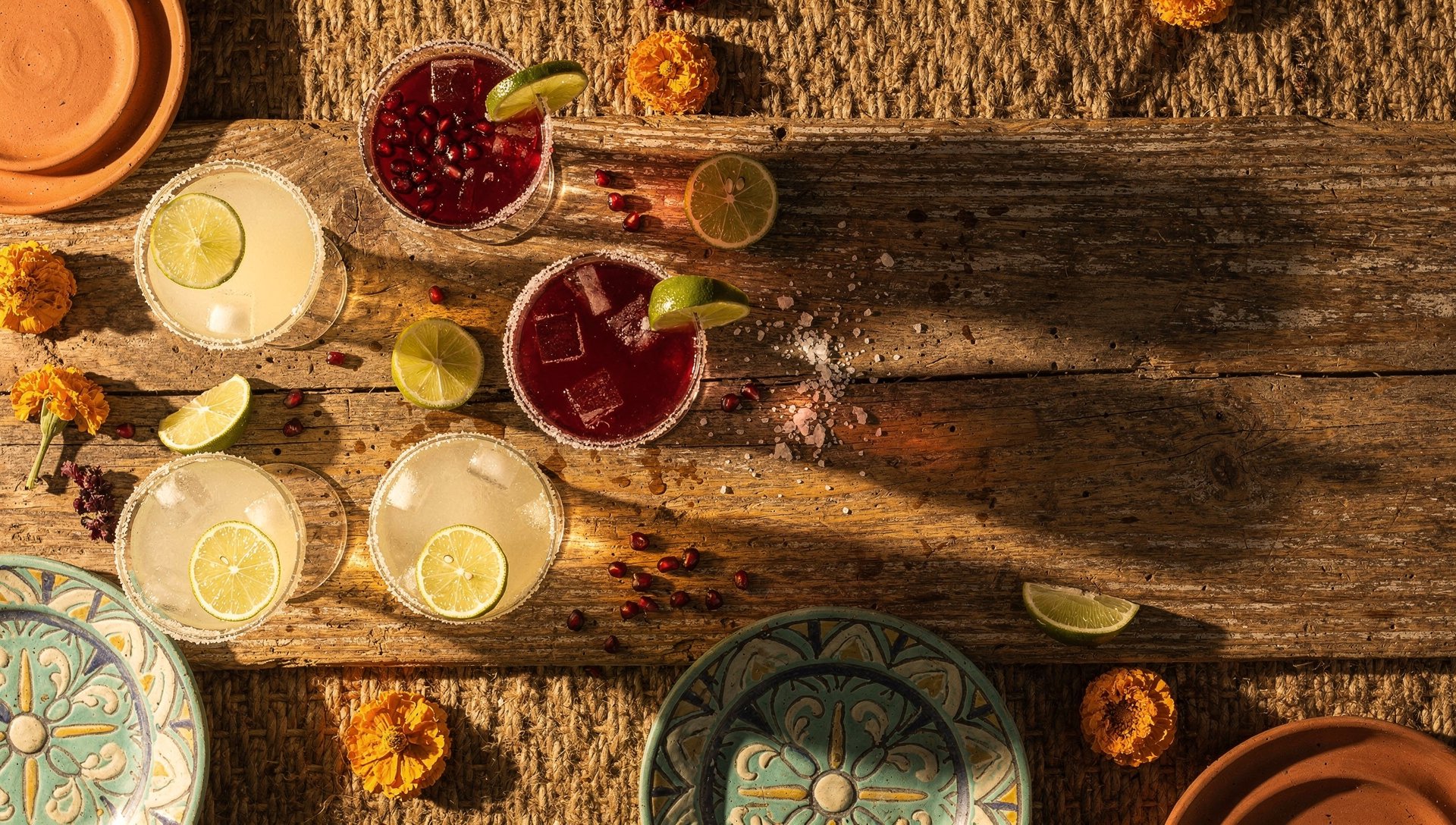 Assorted margaritas including pomegranate margarita on a rustic bar top